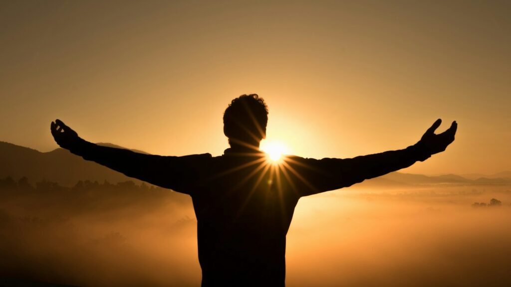 silhouette photo of man on cliff during sunset